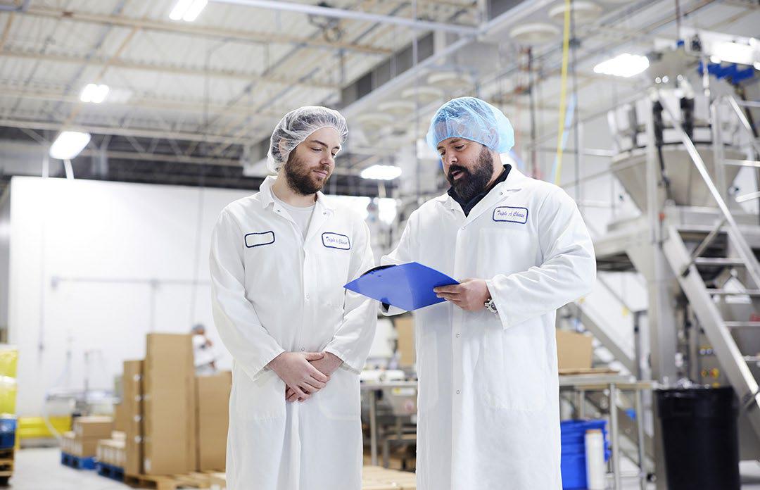 Deux personnes debout dans une usine de fabrication de fromage.