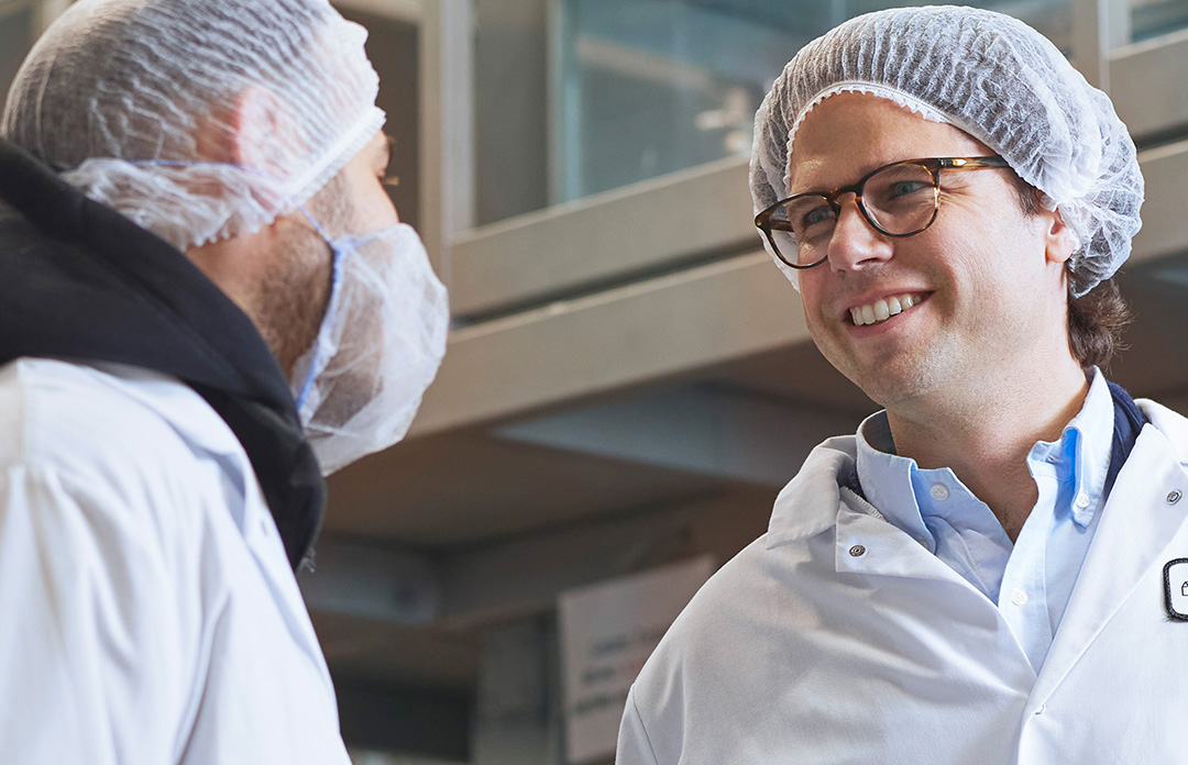 A close-up of men wearing white coats and hair nets 