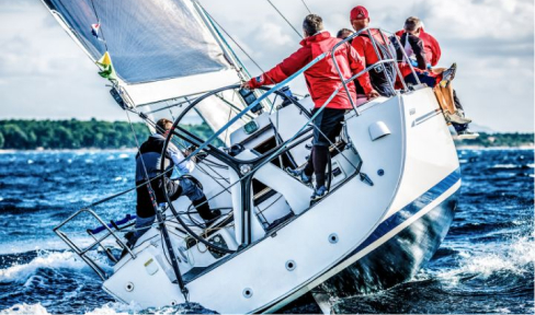 Male sailboat crew dressed in red navigate choppy seas.